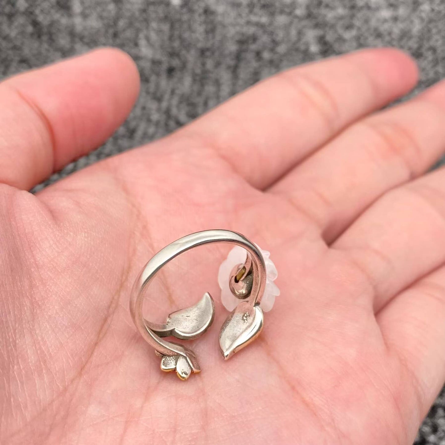 Silver and gold leaf-shaped ring on a hand
