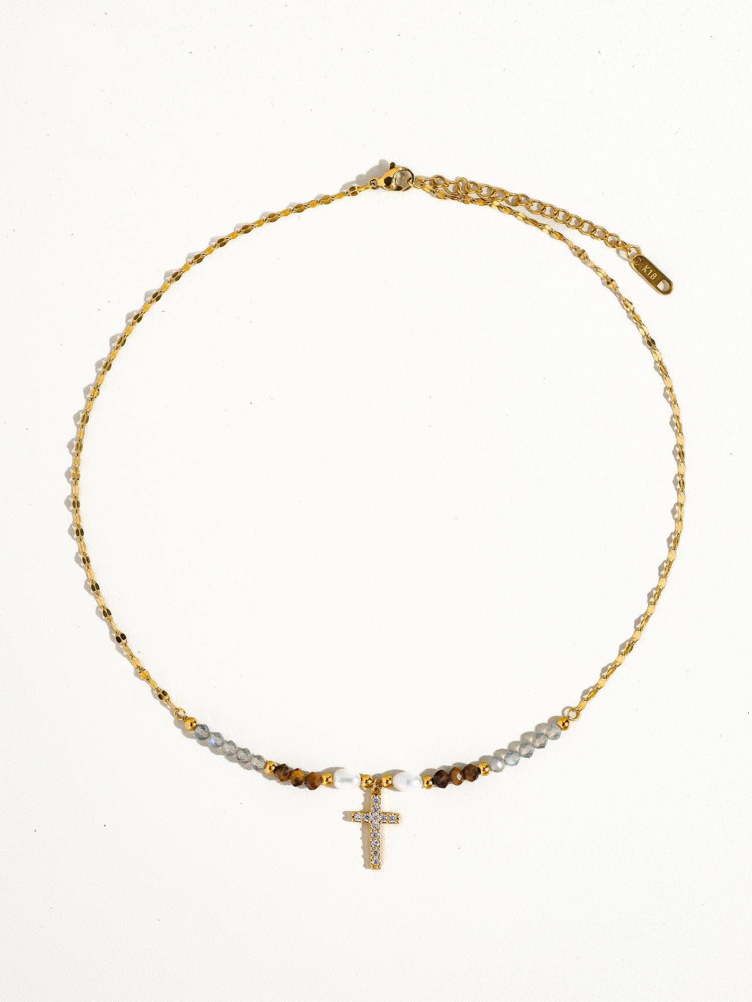 Gold necklace with beads and a cross pendant on a white background